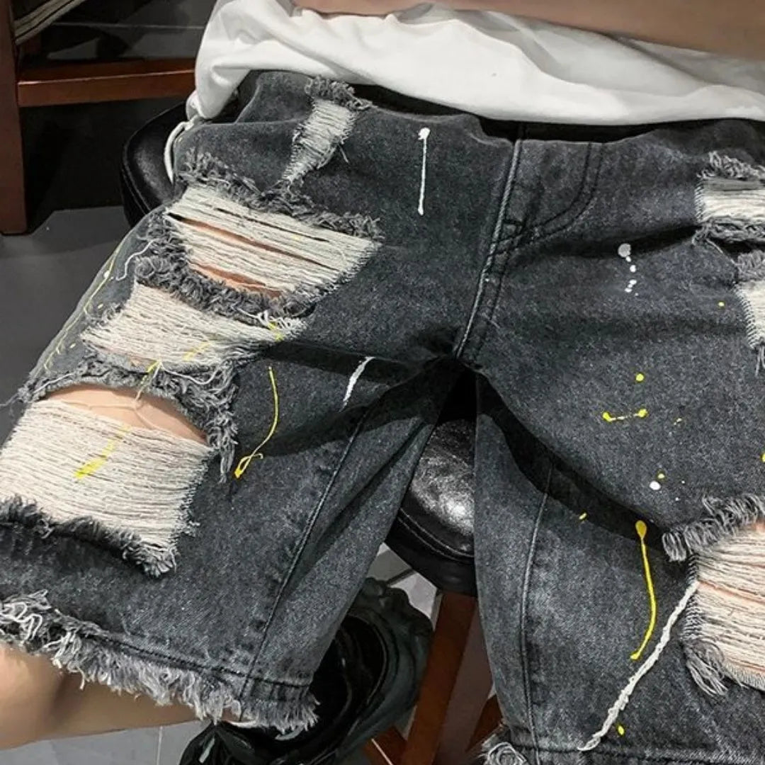 Man wearing loose light blue denim shorts with a distressed hole detail and water-washed finish.
