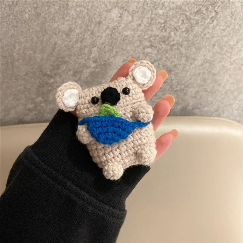 Hand-knitted grey koala bear backpack case for Apple AirPods on a wooden table.