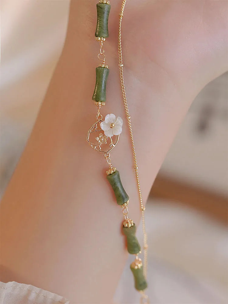 A green olivine stone bracelet with double layers, an Olive Branch charm, and Twin Bells of Ireland pendant.