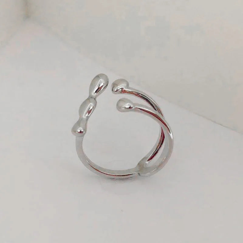 Gold tone brass opening ring with spherical circular design on a finger.