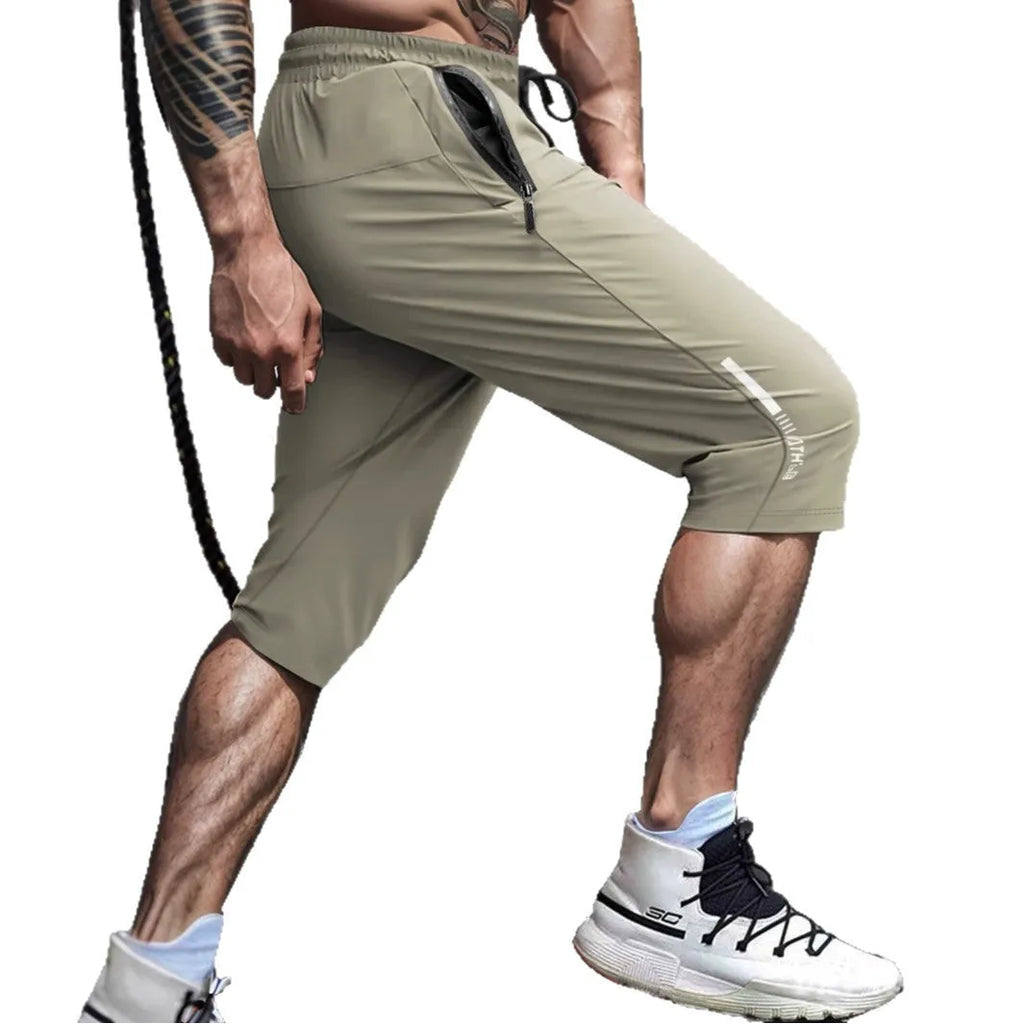 Man wearing cropped black nylon sports pants with a straight cut and elastic waist for summer.