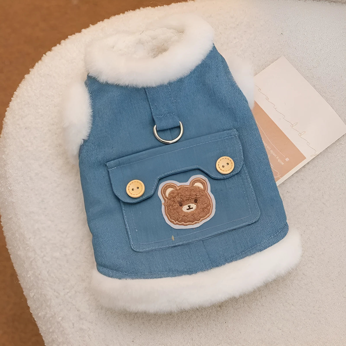 Denim blue pet vest with white wool lining, bear print, wooden buttons, and metal D-ring.