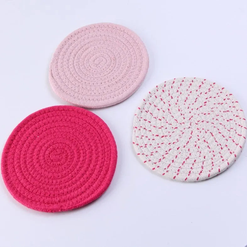 Three round blue cotton cord coaster placemats on a wooden table.