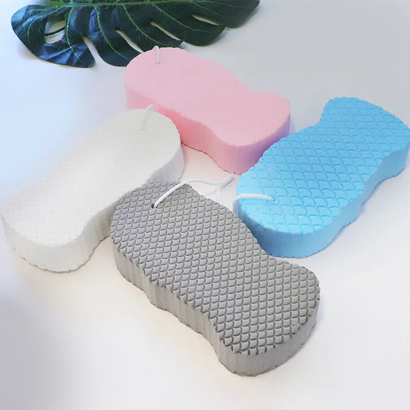 White 3D bath sponge with fish scale exfoliating pattern, shown next to grey, pink, and light blue versions.