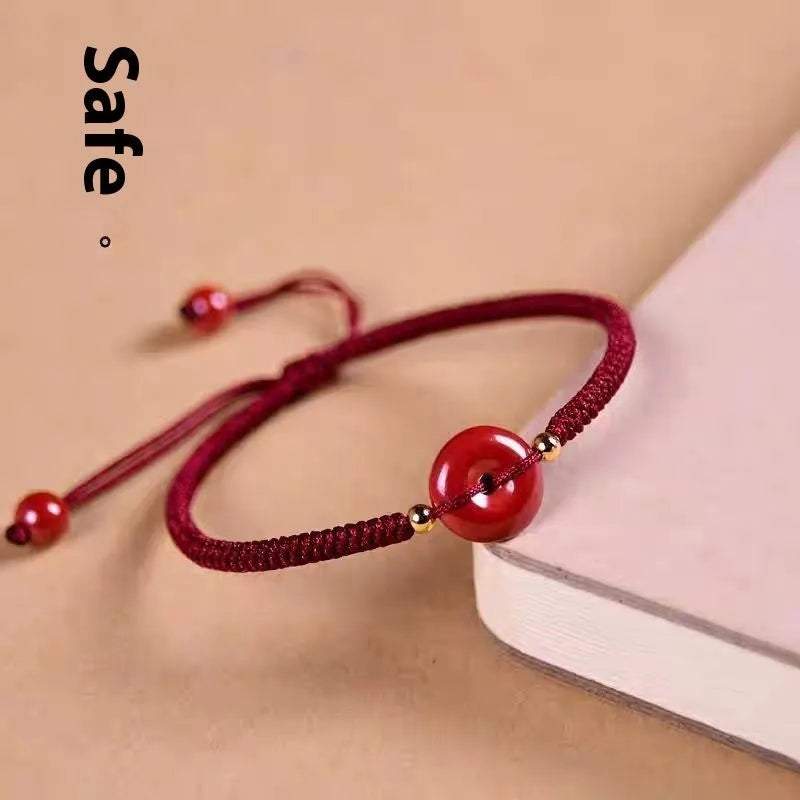 Traditional Chinese cinnabar bracelet with heart-shaped centrepiece and peace buckle clasp on coloured rope cord