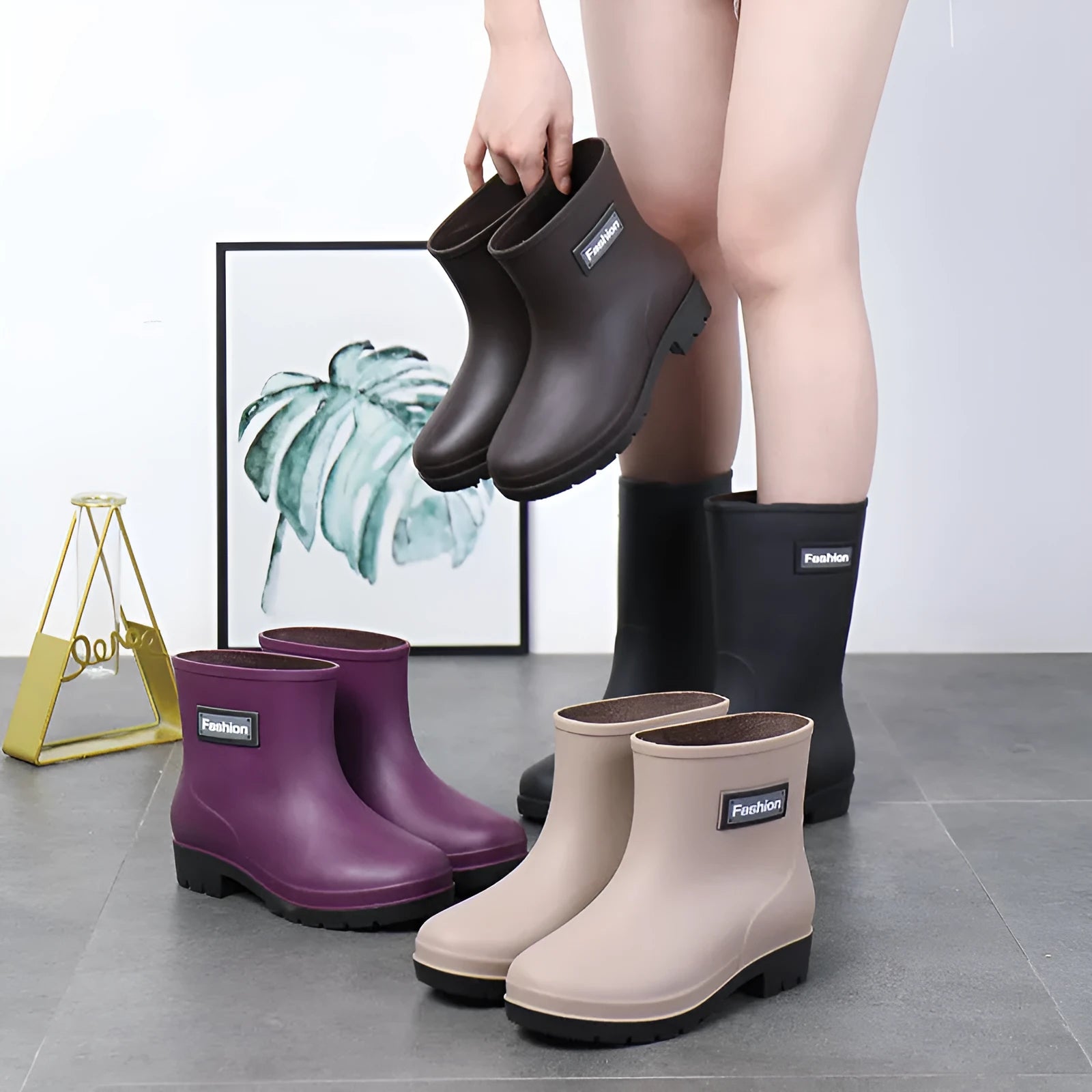 Women's black PVC mid-calf rain boot with a low heel on a wet surface.