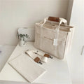 Beige canvas crossbody mommy bag holding baby bottles and wipes on table
