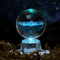 Transparent crystal ball ornament with inner carving on a table, 6cm in diameter with a modern base.