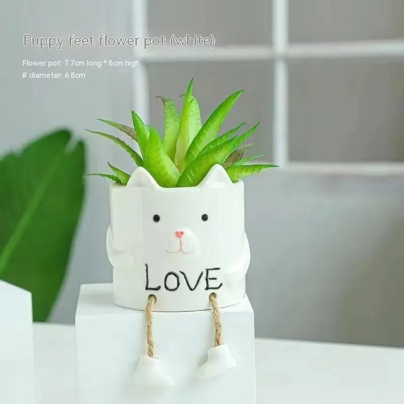 Ceramic hanging foot flowerpot in a cartoon style, shown on a desktop with a small succulent plant.