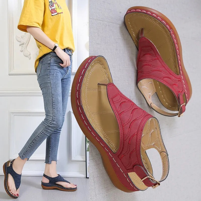 Women's red wedge heel flip flop sandals with an adjustable buckle strap on a white background.