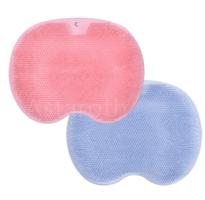 Orange non-slip massage bath brush with suction cups and soft silicone bristles on a bathroom floor.