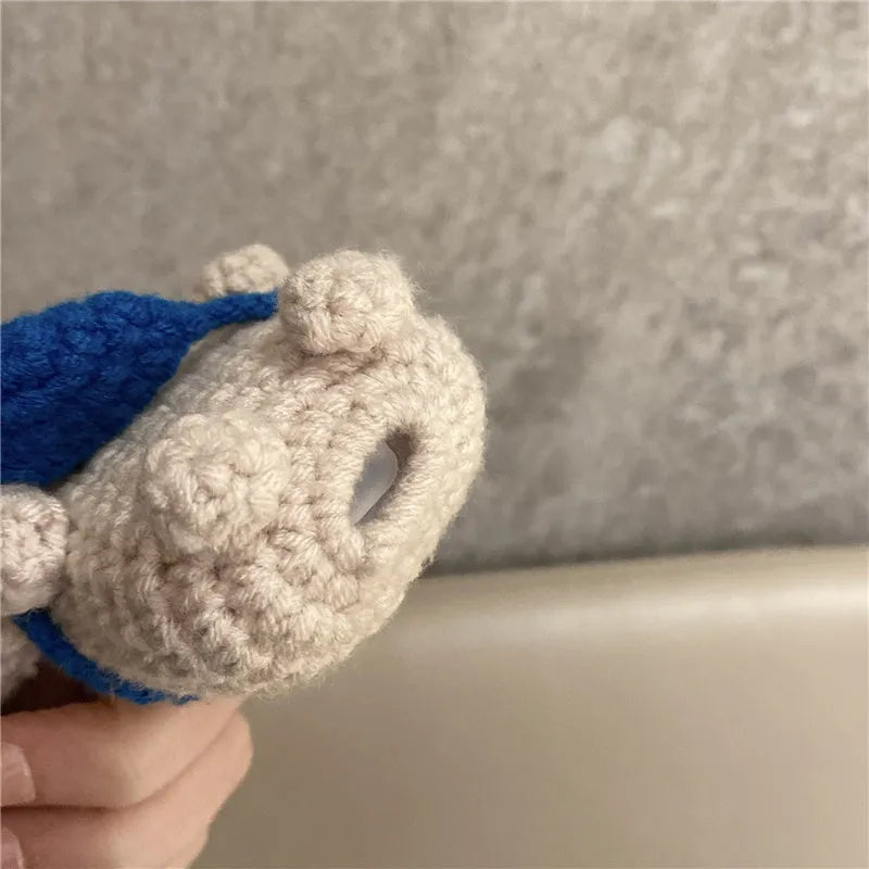Hand-knitted grey koala bear backpack case for Apple AirPods on a wooden table.