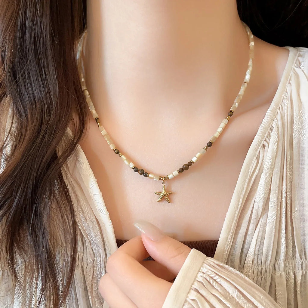 Close view of titanium steel starfish pendant necklace with natural shell and tigereye bead on a woman, Maillard colour, 41-50cm chain