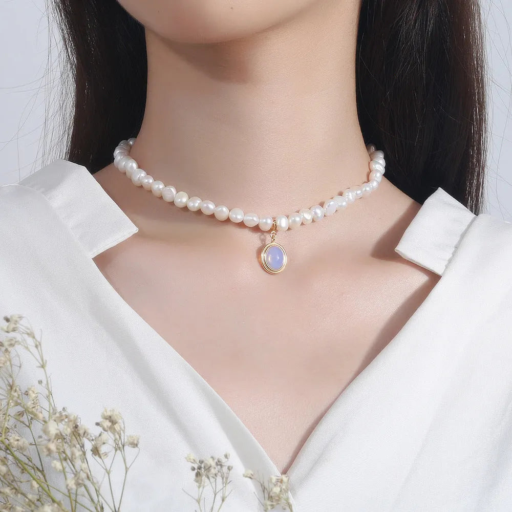 Round geometric sterling silver necklace with an irregular white pearl pendant on a chain.