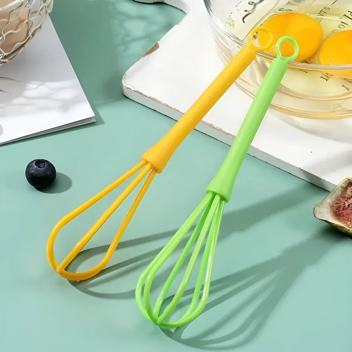 Plastic mini manual eggbeater in green for stirring batter in a kitchen
