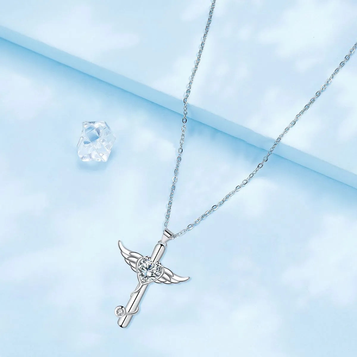 Close-up of a women's necklace with a charm combining a cross, stethoscope, and wings, in a choice of red or white electroplated finish.
