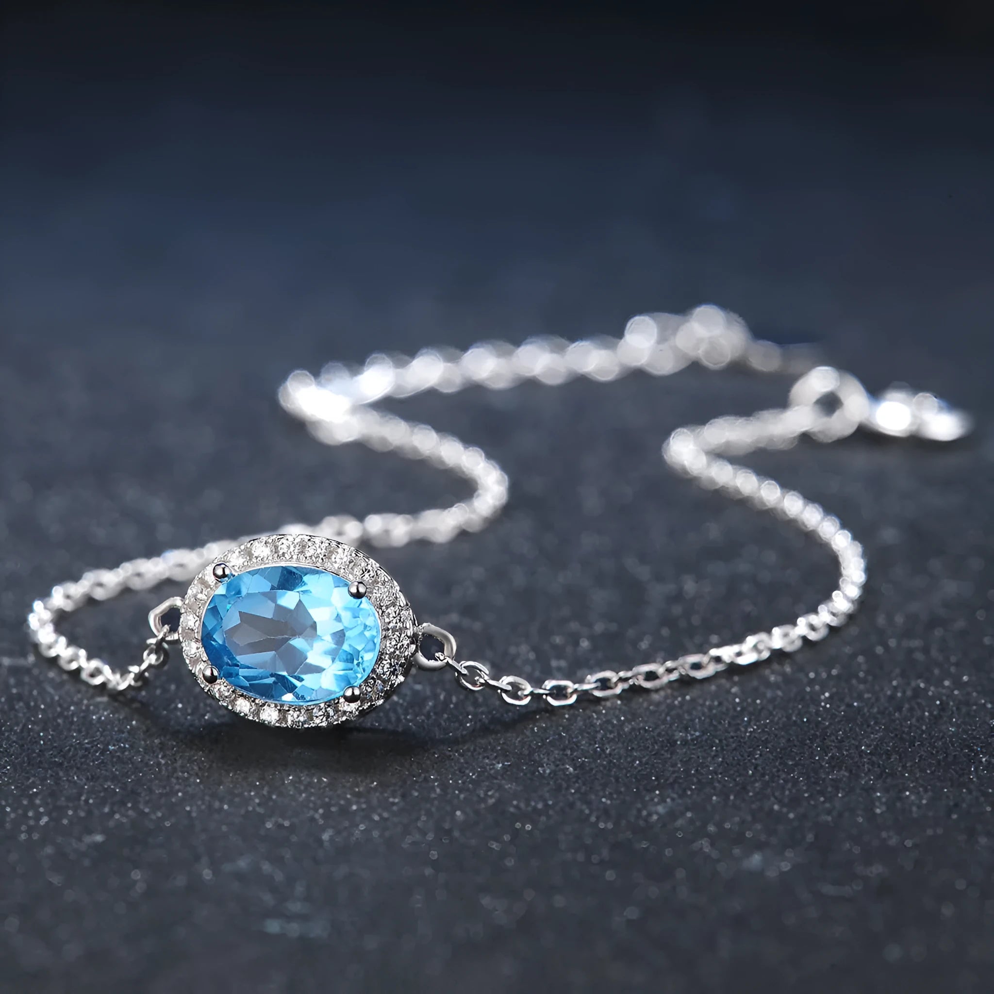 A four-piece women's sterling silver jewellery set with blue topaz gems, showing geometric earrings, ring, pendant, and necklace.