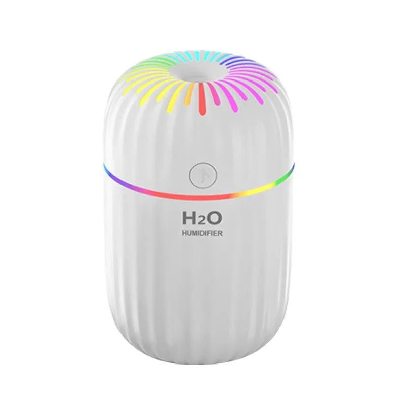 White USB mini humidifier with water tank on a desk next to a laptop