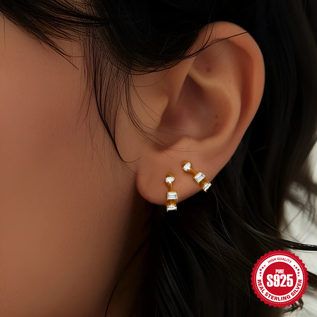A pair of sterling silver stud earrings with a small round geometric drop design, shown in a gold tone finish.