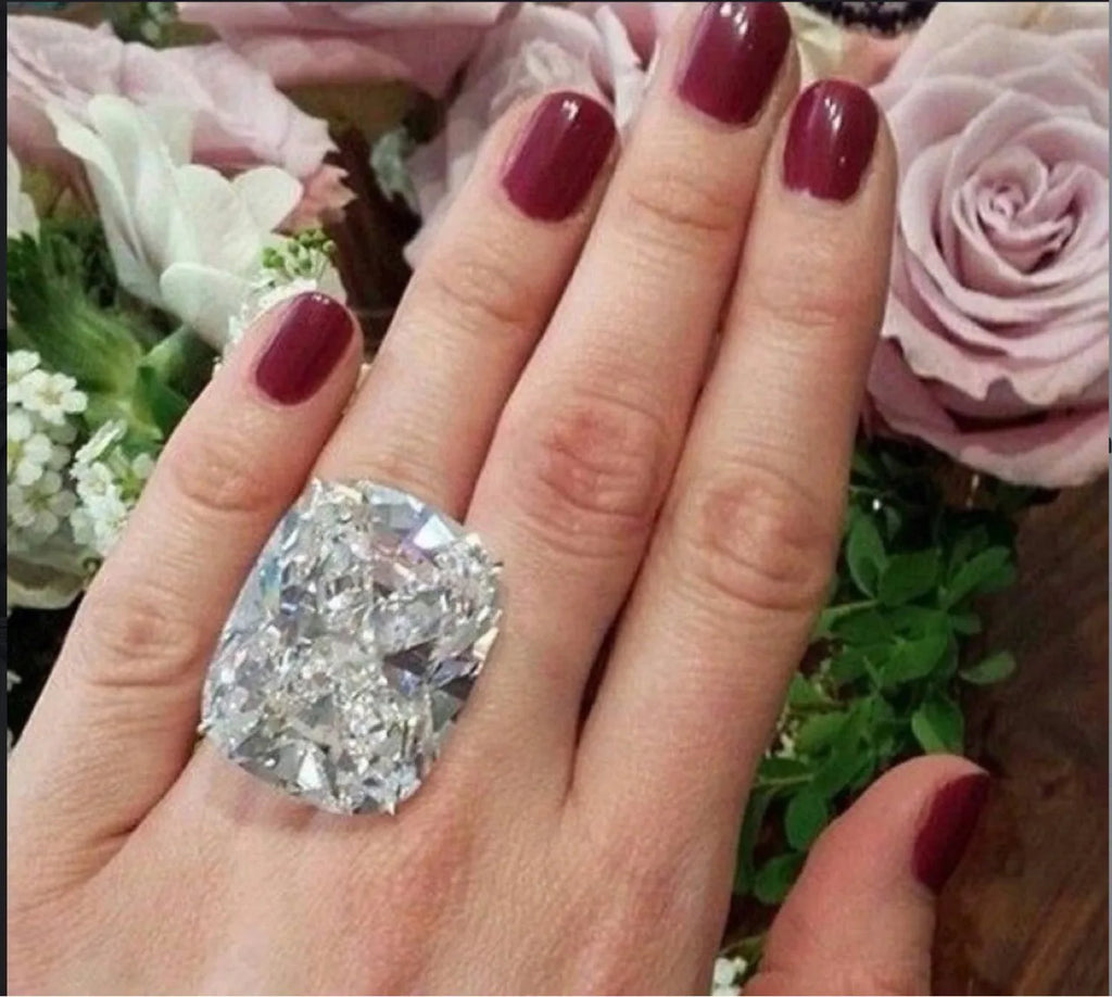Simple white gold colour alloy ring with an inlaid square diamond, shown on a finger.