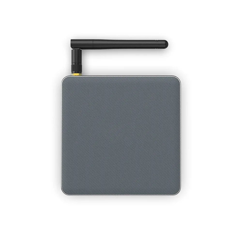 Black Android 8K TV set-top box with remote control, UK plug, and HDMI cable on a wooden surface.