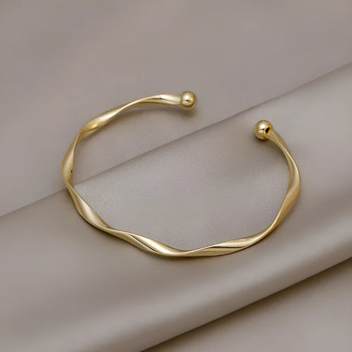 Gold alloy geometric twist bracelet with 6.2 cm inner ring diameter on white background