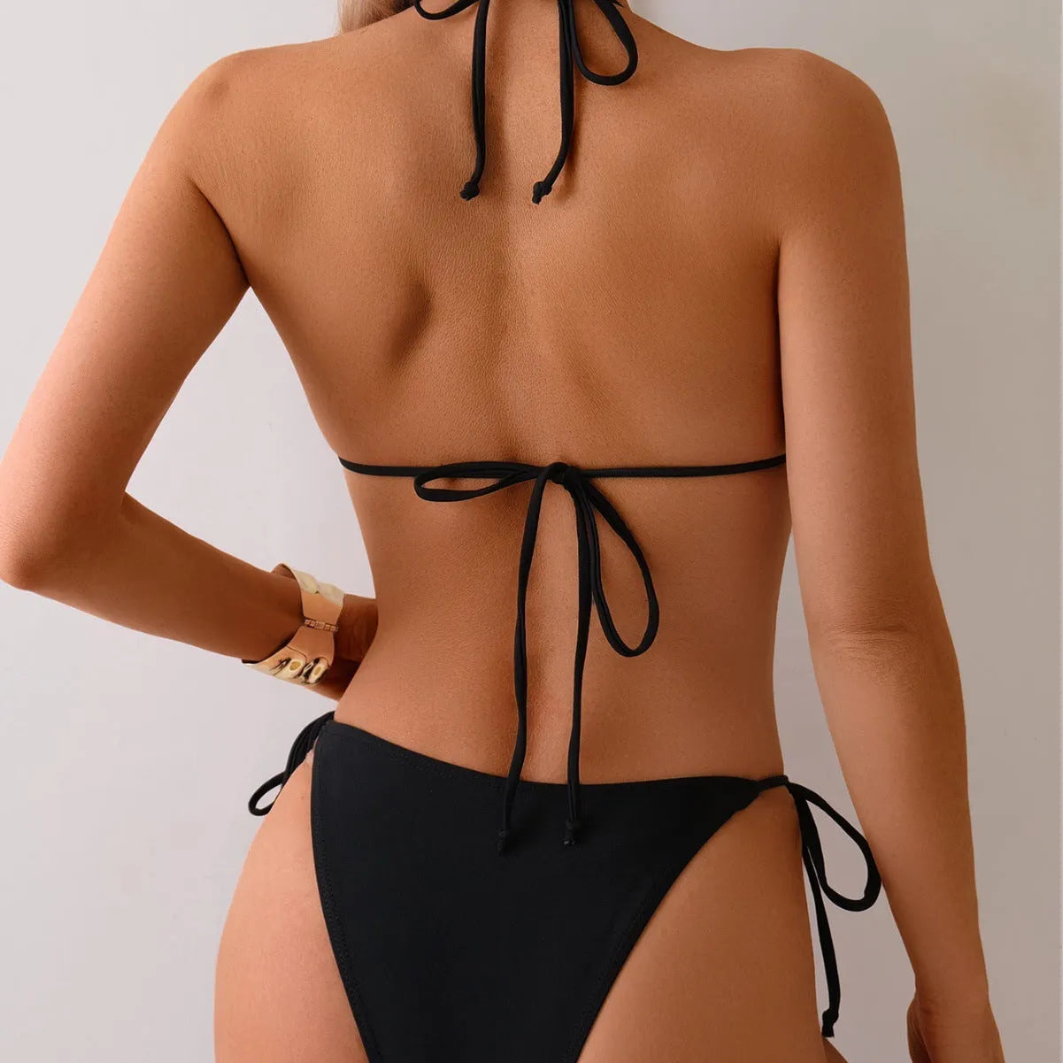 Black women's bikini swimsuit with metal bead decoration on a split design.