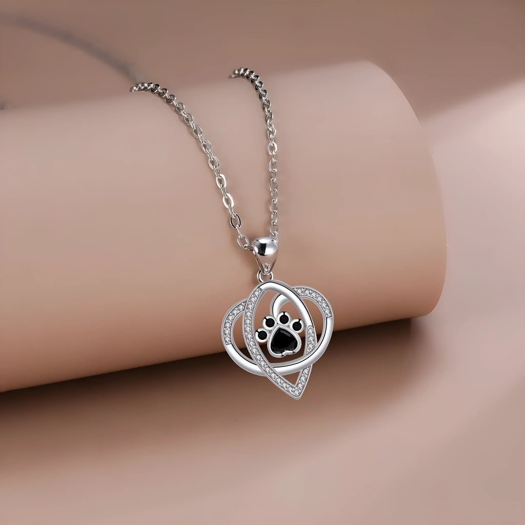 Close-up of dog and cat paw print pendant necklace with cross chain