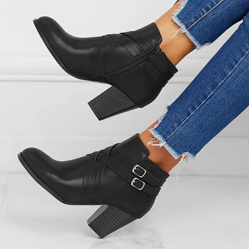 Plus size black short ankle boot with a 7cm heel, side zip, and buckle detail on a grey background.
