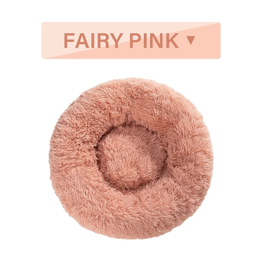 Fluffy donut-shaped dog bed in light grey plush material, showing raised rim and central cushion.