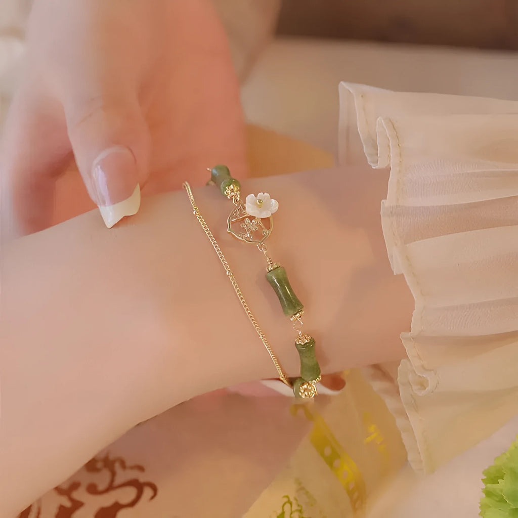 A green olivine stone bracelet with double layers, an Olive Branch charm, and Twin Bells of Ireland pendant.