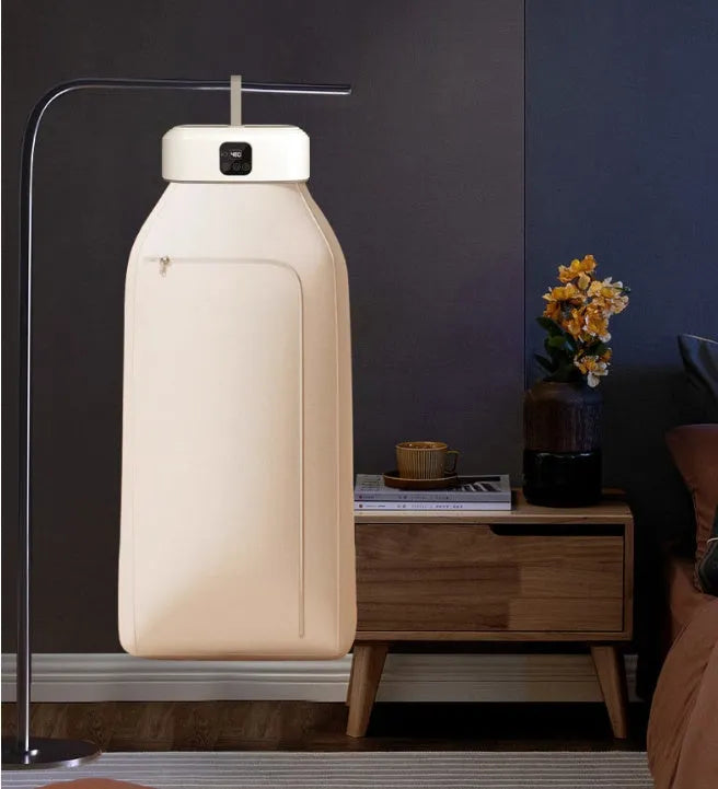 White cylindrical foldable laundry dryer with remote control on a table.