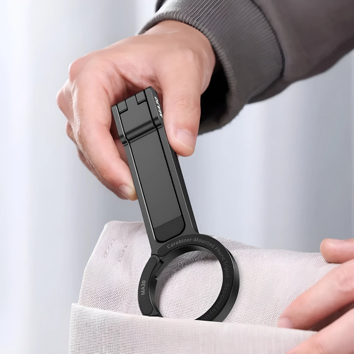 Portable phone holder with black climbing button carabiner on grey background, aluminium alloy and silicone construction