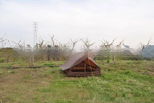 Brown A-line cabin tent pitched using hiking poles with aluminium ground nails and fluorescent wind ropes