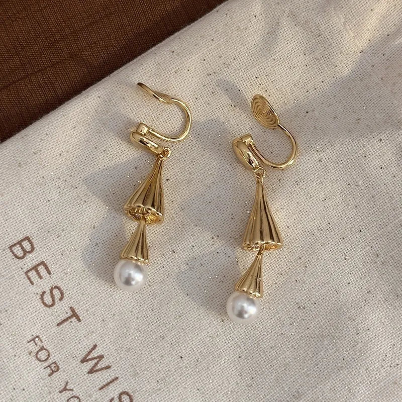 Gold electroplated copper geometric fringe earrings on a woman with long wind chime pearl mosquito coil plate shape close up