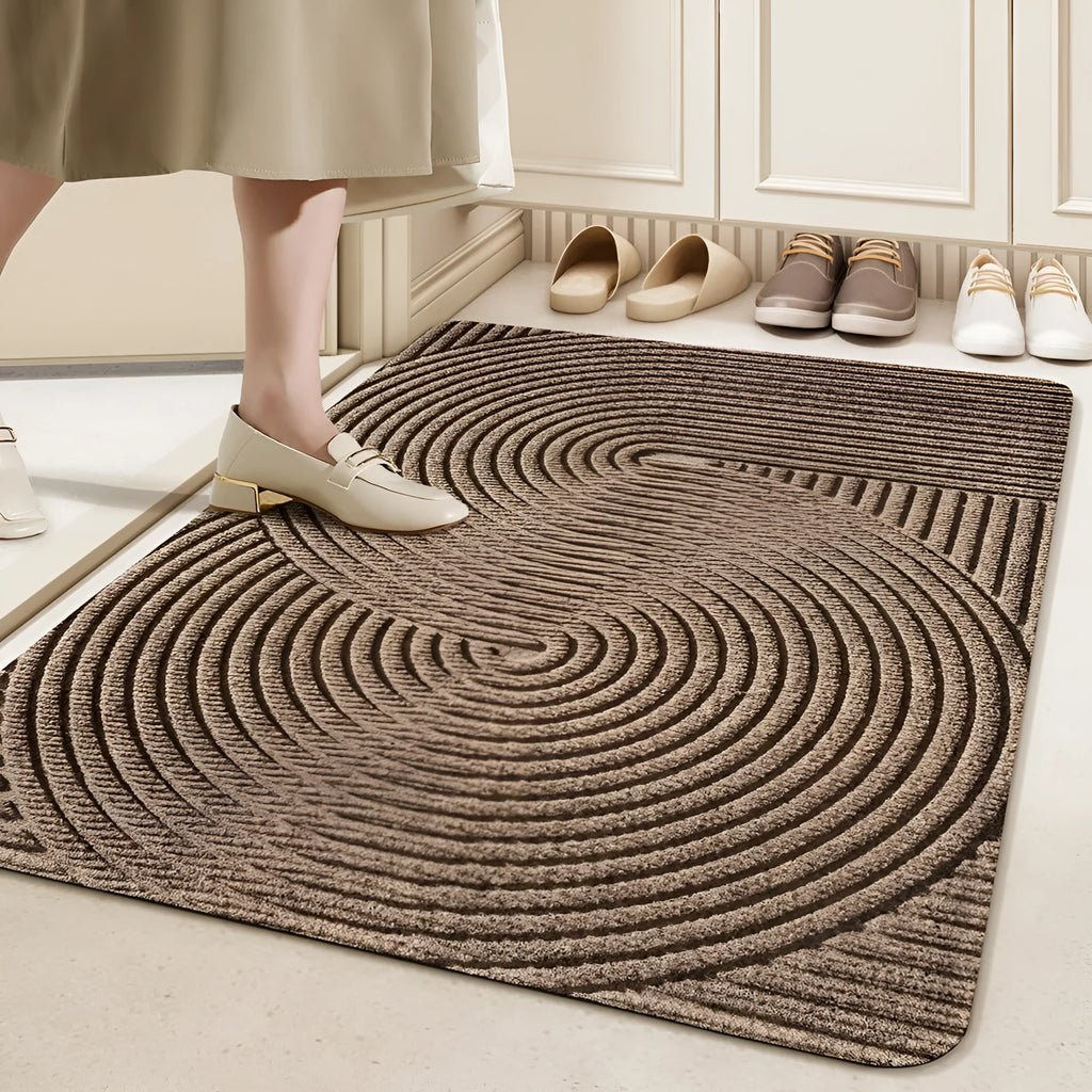 Green alien-shaped entrance mat with cartoon pattern on a wooden floor.