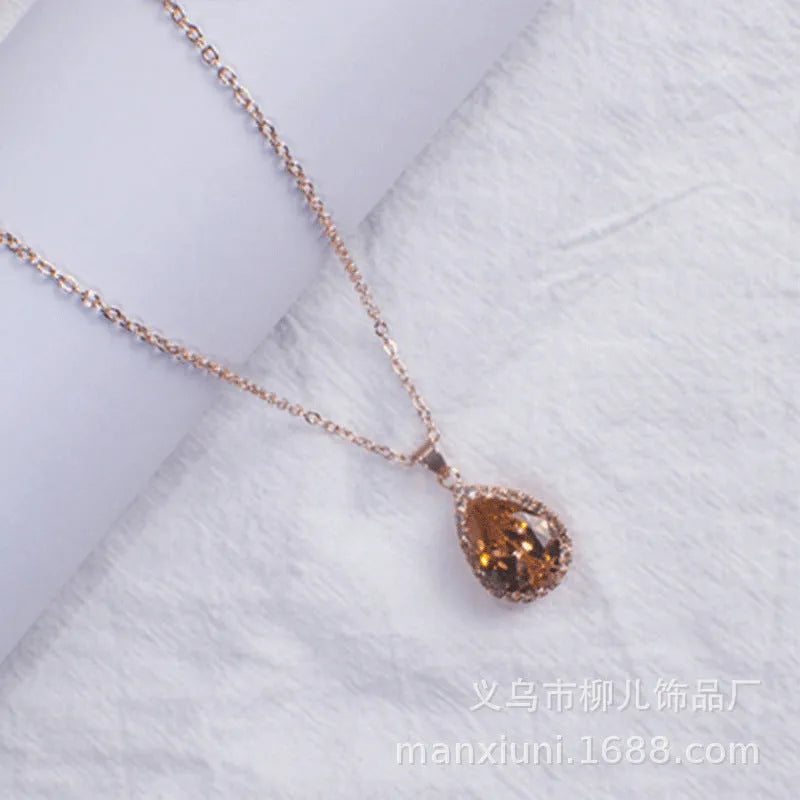Close-up of a women's pink rose gold drop necklace with geometric rhinestone patterns on an alloy setting.
