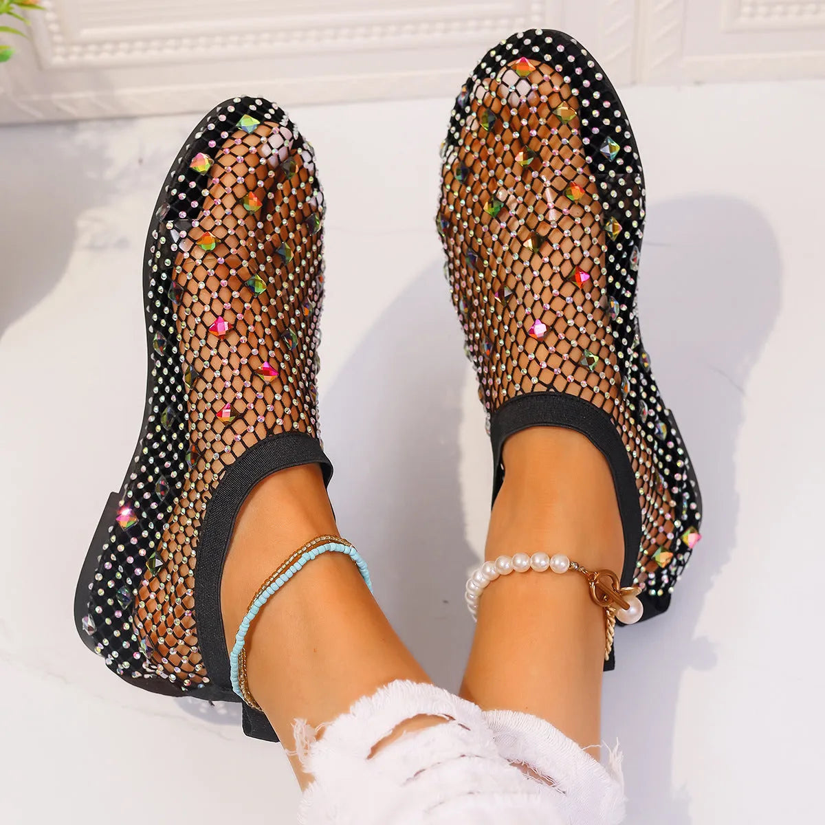 Colourful rhinestone detail on women's white mesh flat sandals with a round toe and rubber sole.
