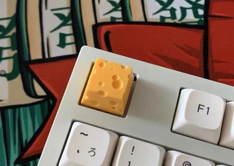 Close-up of a yellow resin cheese-shaped keycap for a mechanical keyboard.