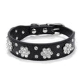 Close-up of a black PU leather dog collar with a rhinestone flower pattern and metal studs.