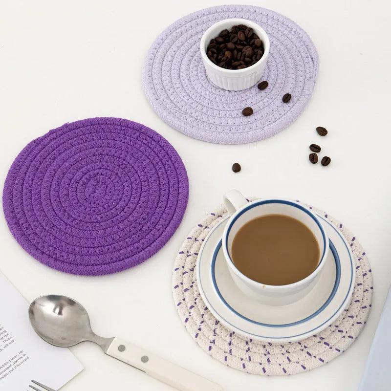 Three round grey cotton cord coasters placed on a wooden table, each 18cm in diameter.