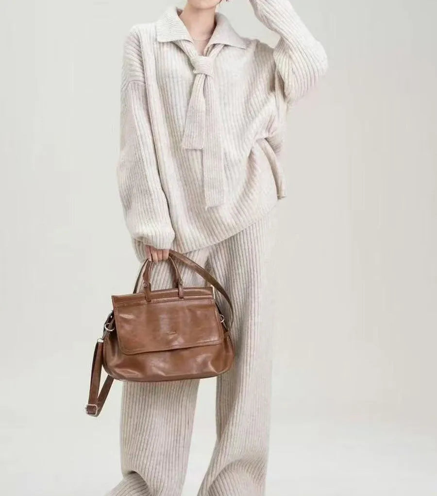 Women's beige knitted top and matching trousers from a two-piece acrylic sweater suit set laid flat.