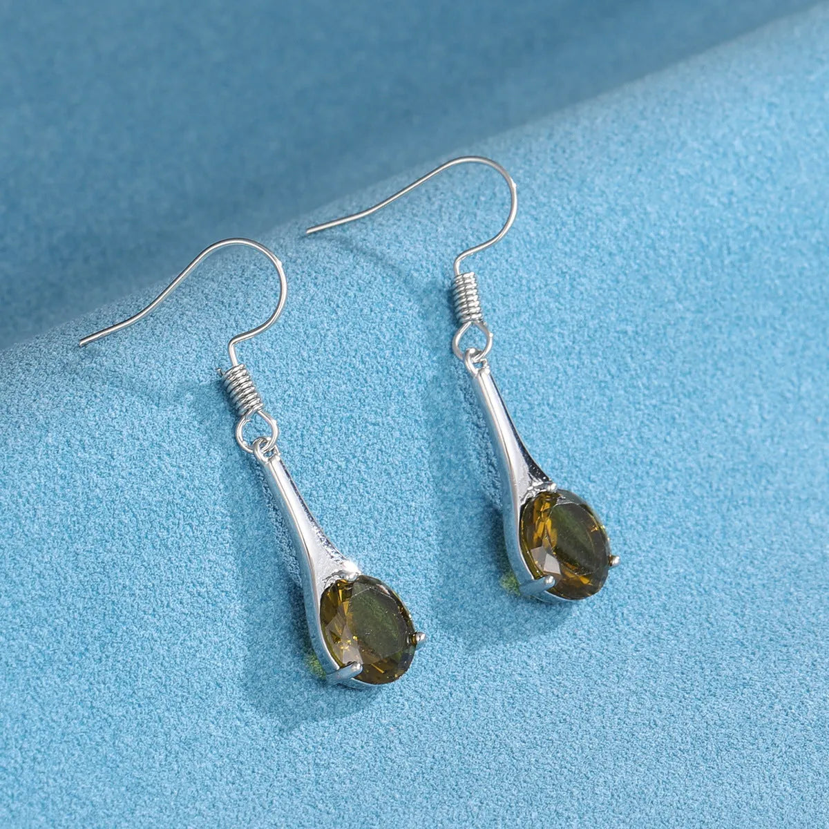 Olive green topaz coloured water drop shape earrings with minimalist retro styling on white background