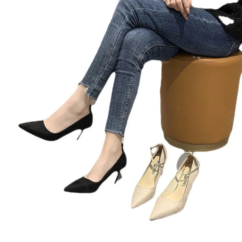 Women's black stiletto pump with skull pattern and buckle decoration on a white background.