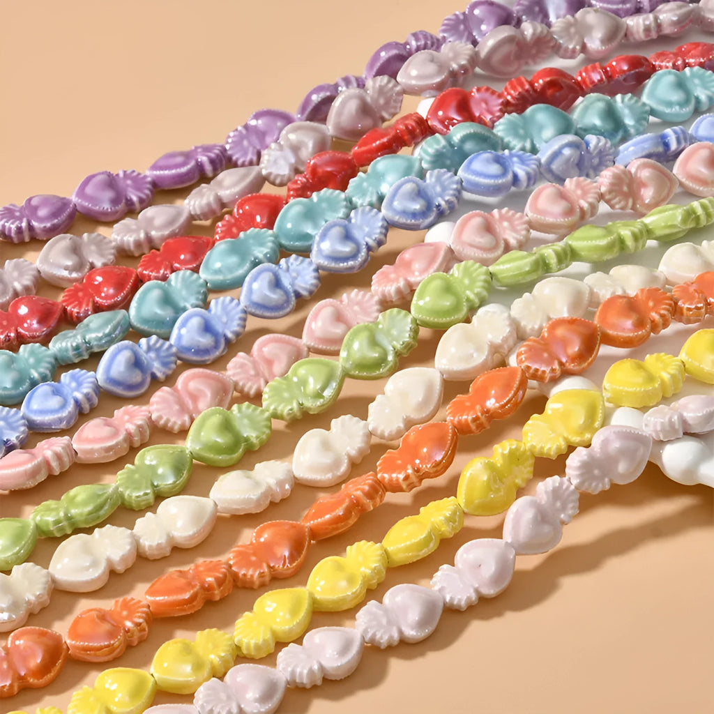 Small heart-shaped ceramic beads in multiple colours showing straight hole, approximately 10mm by 15mm size