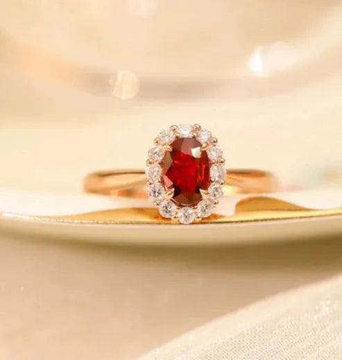 Silver plated ring with gold pigeon design and red blood gemstone inlay on a floral pattern band.