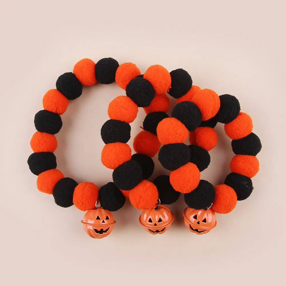 Orange pumpkin print cat collar with plastic buckle and small metal bell attached.
