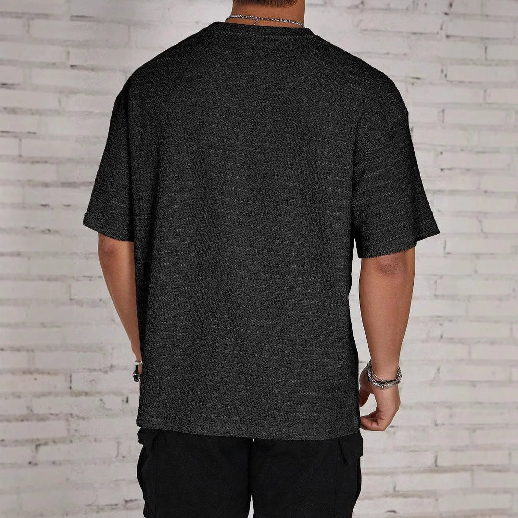 A man wearing a slim-fit, solid-colour, short-sleeve round neck T-shirt.
