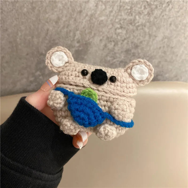 Hand-knitted grey koala bear backpack case for Apple AirPods on a wooden table.