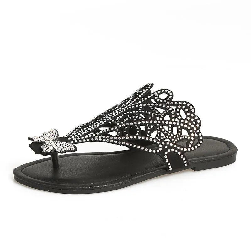 Women's black slip-on sandals with flip-toe design, rhinestone decoration, hollow-out detailing, and a flat rubber sole.